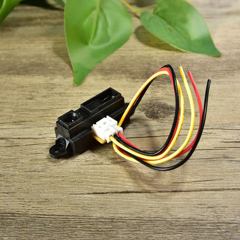 Sharp IR Analog Distance Sensor GP2Y0A21YK0F 10 To 80 Cm Cable lying on a wooden surface, black casing with attached wires.