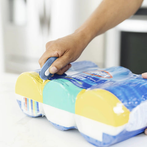 Blue Slice Mini Box Cutter with retractable blade slicing plastic wrap on a 4-roll paper-pack