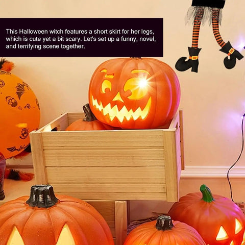 Halloween scene with carved glowing pumpkins and suspended witch legs in black shoes and orange striped stockings