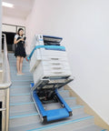 Heavy Duty Electric Stair Climbing Hand Truck With Dual Motors And Smart Load Balancing Board handles a copier going up stairs.