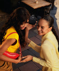 Two women laughing outdoors while holding a SoundLink Micro Portable Bluetooth Speaker 2nd Gen For Outdoors, Black For Adventure