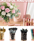 Rose gold wire holders and accessories on a wooden desk with flowers and lipsticks in a decorative setting.