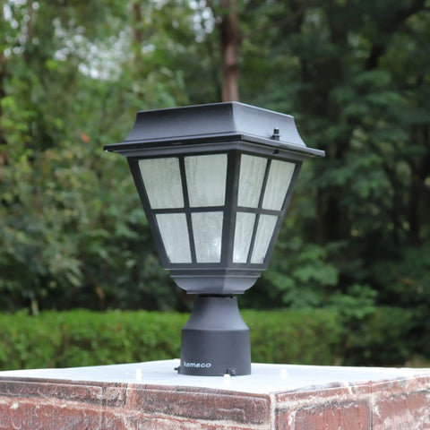 Solar Powered LED Post Cap Light for 3 Inch Fitter Mount Outdoor Cast Aluminum Lamp With Bright Warm White Glow for Pillar Pathway Driveway Garden Landscape and Yard mounted on a brick pillar with greenery background.