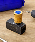 Brass hydraulic flow-control needle valve with blue knurled adjuster, 1/2 in NPT ports, mounted on black block (front view).