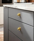 Real Deal Solid Brass Cabinet Knobs Slick Flower Backplate Brushed Gold Finish on gray drawer pull in kitchen setting.
