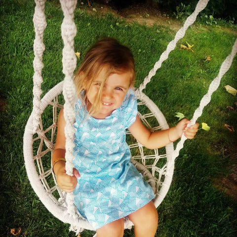 Child sitting in Kids Hammock Swing Chair For Indoor And Outdoor Fun, Handmade Macrame Knitted Hanging Seat For Toddlers Aged 2 To 5