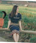 Person sitting on a wooden fence in a rural field, with a basket and a Heavy Duty Weeding Blade Hand Hoe for Gardening nearby