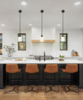 Modern kitchen with island, brown bar stools, and three pendant lights over counter with sleek decor