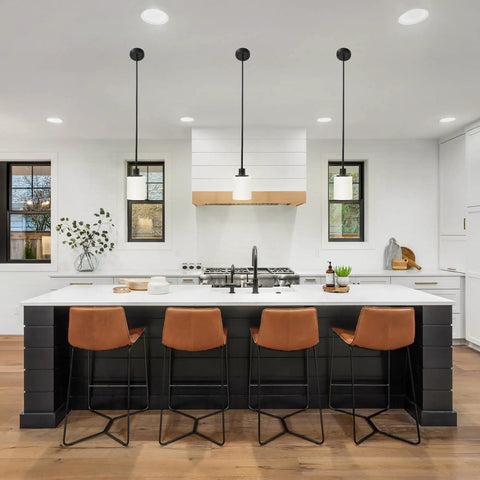 Modern kitchen with island, brown bar stools, and three pendant lights over counter with sleek decor