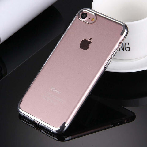 A smartphone with a transparent protective case on a black surface beside a white cup.