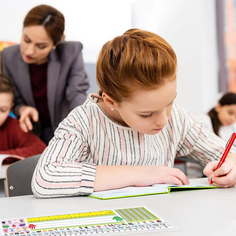 Student writing at desk with Stick On Nameplate Pockets For Desks, 40 Pack, Clear Adhesive Covers Measuring 4.7 X 14.2 Inches