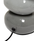Close-up of Shades Of Gray Ceramic Stacked Stone Table Lamp With Fabric Shade, showing gray ceramic base with cord.