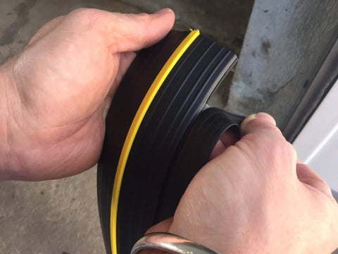 Close-up of hands holding Beefed Up Garage Door Threshold Seal Kit With Adhesive And Bottom Weather Stripping for 10 ft 6 in doors