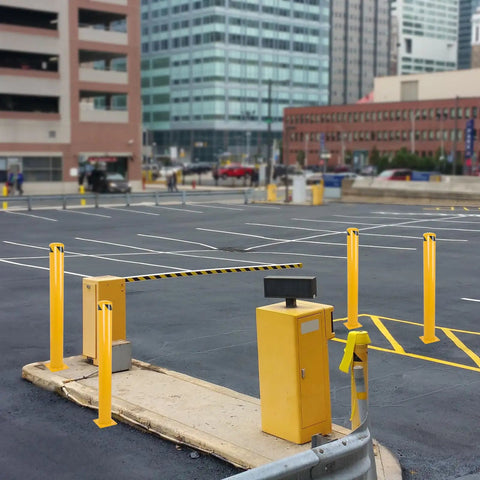 Heavy Duty Steel Safety Bollards Industrial Yellow Powder Coat Includes Anchor Bolts Rock Solid Driveway Guard Post in a parking area.