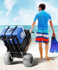 Man pulling beach cart with balloon wheels and large deck on sand, heavy duty load up to 165 pounds adjustable height foldable wagon