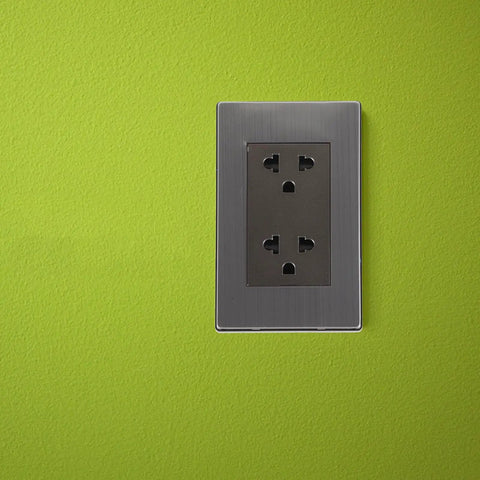 Heavy Duty Stainless Steel Tamper Resistant Wall Outlet Socket Featuring Circular 6 Hole Design and Swanky Metal Faceplate for US Homes Offices and Solid Electrical Safety Vibe on green wall.