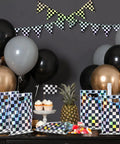 50 Pack Iridescent Checkered Race Car Party Favor Bags with balloons and checkered banners on display table.