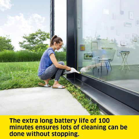 Kärcher WV 6 electric window vacuum squeegee; side view of a person kneeling outdoors, cleaning a large glass door.