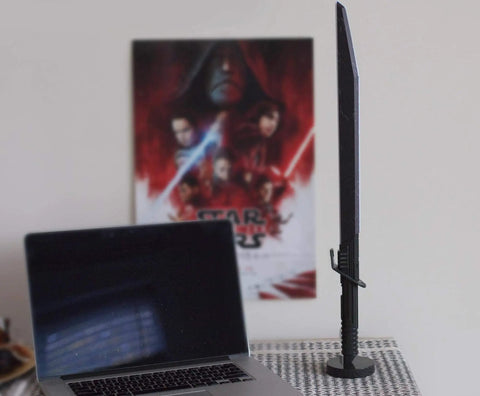Star Wars The Mandalorian Darksaber 24-Inch LED Desk Light Lamp for Fans next to a laptop on a patterned surface.