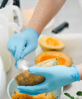 Hands wearing Vinyl Exam Gloves X Large Latex Free Powder Free Case Of 1000 For Allergy Sufferers while handling melon