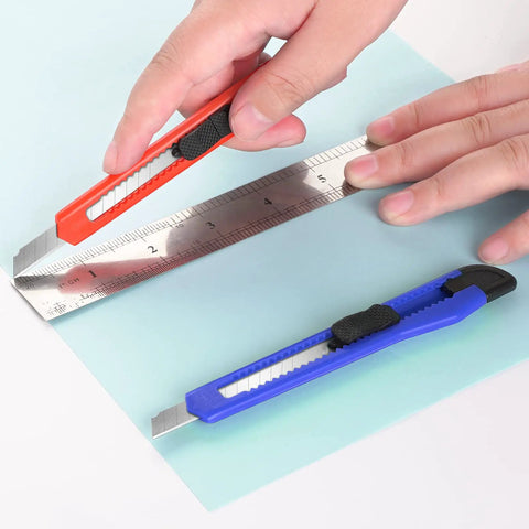 Hands using 24 Pack 9mm Wide Box Cutters Retractable Utility Knife Set For Heavy Duty Office Home Use Arts Crafts And DIY Projects Grab And Go Grips Workhorse Design Extended Use With Disposable Blades to cut paper.