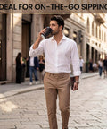 Man on street holding 50 Pack 12 Oz Disposable Coffee Cups With Lids And Straws Insulated To Go Paper Cups With Detachable Corrugated Sleeves For Hot Or Cold Drinks Ideal For Office Travel Coffee Bar And Grab And Go Black Sleeves