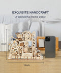 Fortress Tower Marble Run Puzzle Kit With Interlocking Gear Mechanics 3D Wooden Coaster Build displayed on a table next to a smartphone.