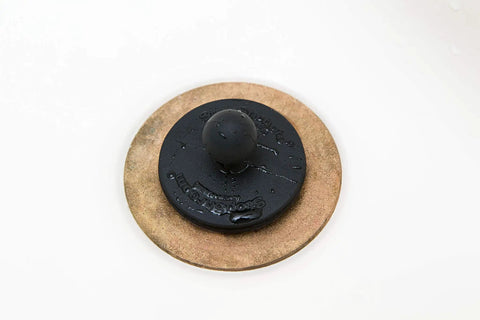 Universal Drain Stopper For Bathtub And Sink Your Go To Two Pack Black Plug in use on a white sink surface, made from durable silicone.