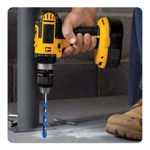 Cordless yellow drill with blue masonry drill bit drilling into a concrete surface.