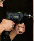 Person using Pro-Grade 5 Amp Half Inch Hammer Drill Kit With 105 Accessories, Variable Speed To 3000 RPM, on wood