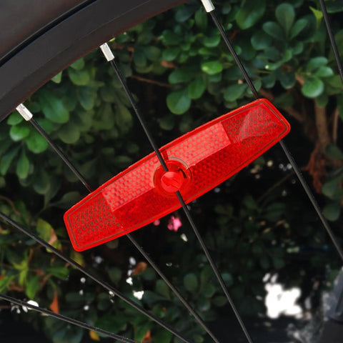 Close-up of a red bike wheel reflector installed on a spoke, part of the Bike Wheel Reflectors 10 Pack With Clips For Night Riding And Safety Red Spoke Reflectors For Road Mountain And City Bikes High Visibility Bicycle Accessories To Boost Visibility And Style.