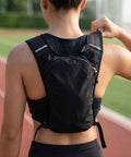 Person wearing hydration vest pack with breathable nylon, adjustable chest straps on running track