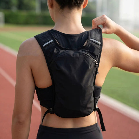 Person wearing hydration vest pack with breathable nylon, adjustable chest straps on running track