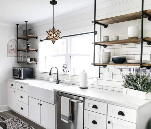 Seeded Glass Moravian Star Pendant Light With Black Industrial Finish illuminating a modern kitchen with white cabinets and shelves.