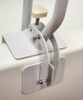 Close-up of white bathtub rail with wide grip for bathroom safety installed on tub edge, showing clamp mechanism for secure attachment.