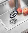 Two Pack Stainless Steel Kitchen Sink Stopper Sets With Large Wide Rim Three Point Three Five Inches Diameter No Tools Needed Easy Replacement For Splash Guards Keeps Food And Debris From Splashing Up Fits Standard Drains Value Packed displayed in a modern kitchen sink setting with apples nearby.