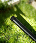 20 Pack 1/2 Inch Drip Irrigation Barbed End Plug Fittings And End Cap Connectors For 1/2 Inch Tubing 0.520 To 0.650 ID OD Garden Lawn Irrigation System No Fuss Setup installed on black tubing in a grassy garden.
