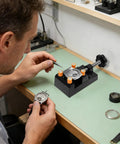 Person using Heavy Duty Mini Drill Press Vise Clamp For Jewelry Milling And Wood Carving to secure watch parts on a workbench.