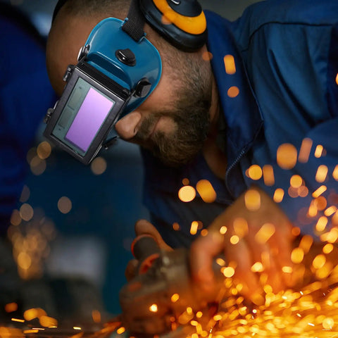 Man using Boss Grade Auto Darkening Welding Goggles Heavy Duty Industrial Safety Glasses With Lightning Shade Switch For Grinding Soldering And Precision Steel Fabrication In Navy Blue while working with sparks flying.