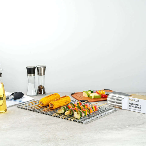 Foil Lux Disposable Grill Liners 19.7 By 12 Inch Nonstick Aluminum Grill Sheets next to grilled vegetables and corn on the counter