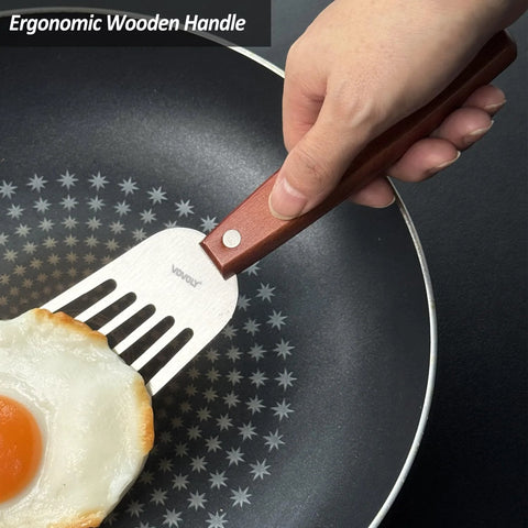 Slotted fish spatula with wooden full-tang handle and stainless steel blade flipping a fried egg in a pan