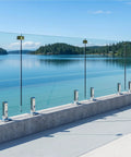Top Tier Six Panel Laminated Glass Railing Kit For Decks with stainless hardware, smooth view of lake, concrete base, 315 to 324 wide, 44 high.
