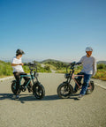 Two riders with Adult Electric Bike With 1000W Brushless Motor 20Mph Peak Pulls 16Inch Slick Wheels on an empty road.