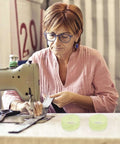 Woman sewing with machine and 20 pack rubber drive belts for sewing machine motors replacement parts visible on table
