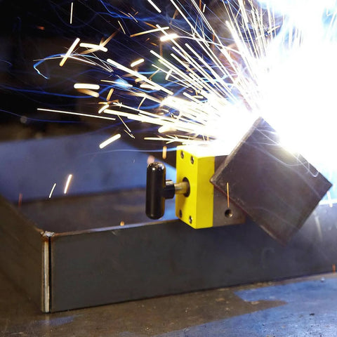 MagSquare magnetic welding clamp demonstrating secure metal fixture with sparks during welding process in workshop.