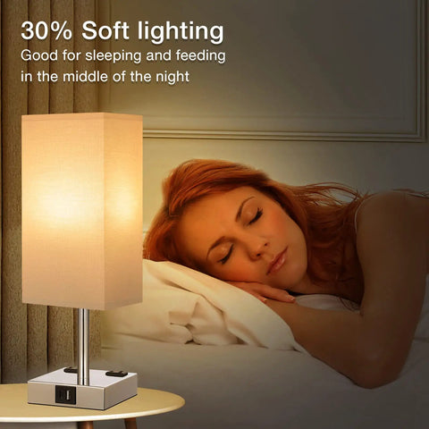 Set Of Two Touch Nightstand Lamps With USB C And USB A Ports AC Outlets Three Way Dimmable Bedside Lamps With White Fabric Shade Perfect For Bedroom Or Guest Room Bulb Included showing one lamp lit on a nightstand