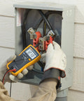 Electrician using True RMS Utility Multimeter For DIY And Pros Measures AC DC Voltage, Resistance, Capacitance, Continuity.