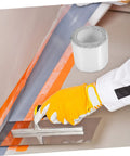 Self-Adhesive Roof Repair Tape With Aluminum Foil Butyl Sealant applied on a seam with a trowel, DIY use, 1 roll visible