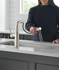 Sleek Brushed Nickel Kitchen Faucet With Pullout Sprayer And Single Handle being used in a modern kitchen with fresh produce.