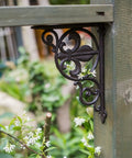 Heavy Duty Iron Corner Braces Tough As Nails Floating Shelf Supports Wall Mounted Triangle Plant Stand Steel L Brackets Set Of Two No Sweat Install Rugged Hardware Gear decorative black iron corner bracket on wooden post with flowers.